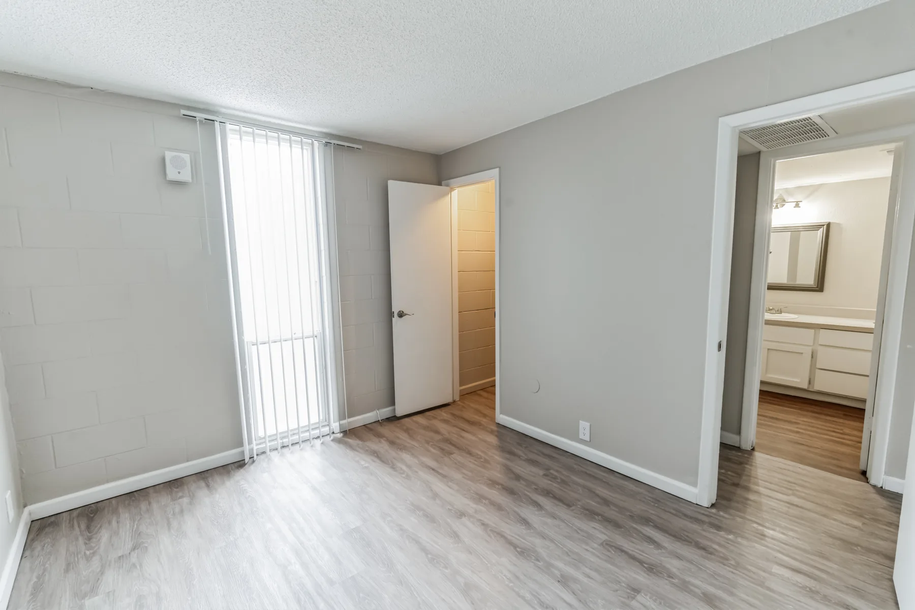 Bedroom with wood-style flooring, sliding glass door and en-suite bath at Uptown Horizon Apartments