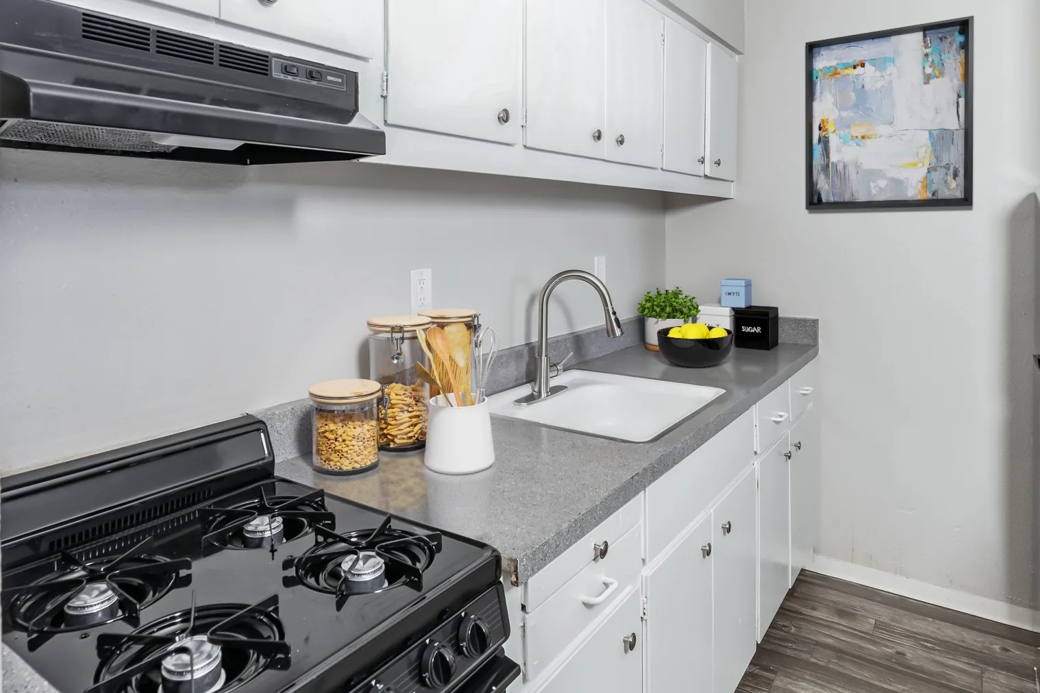 Kitchen with gas range, white cabinets and gray counters at Uptown Horizon Apartments