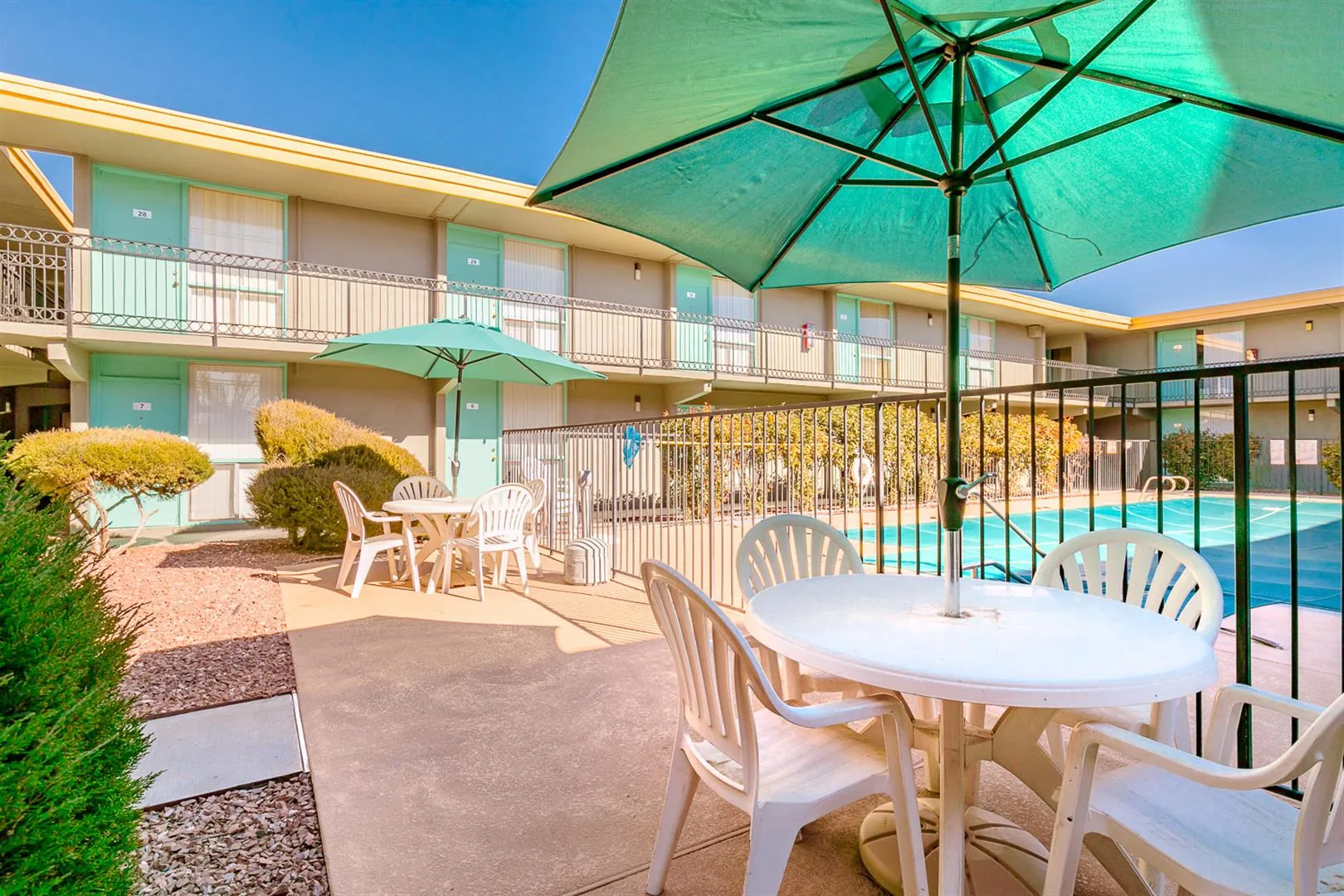 Pool deck with patio tables and green umbrellas at Uptown Horizon Apartments